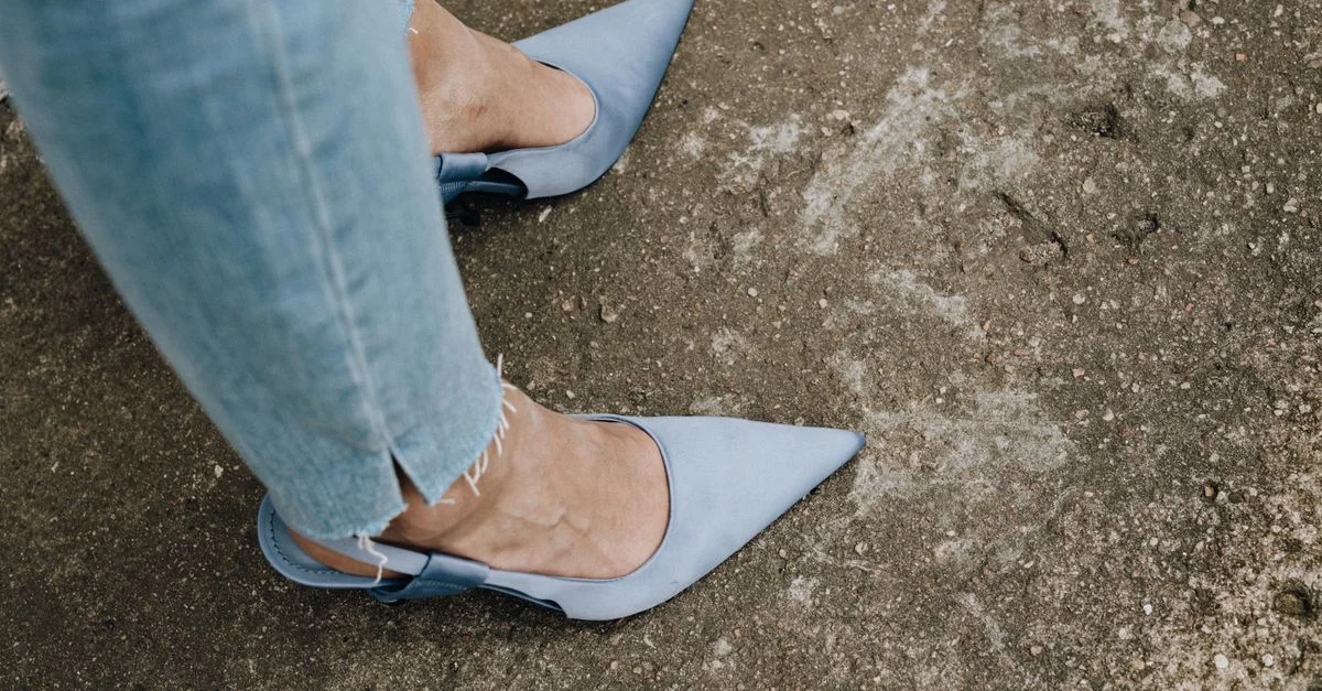 Primer plano de tacones azules puntiagudos combinados con jeans, perfecto para individuos a la moda.