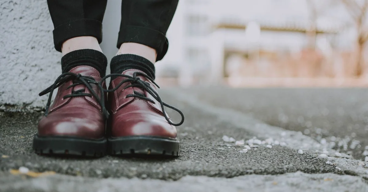 Zapatos de cuero a la moda con cordones negros en una acera urbana.